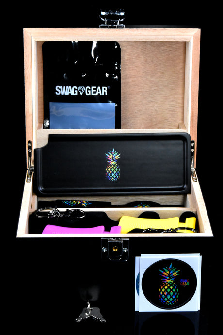 Interior of locking wooden stash box with tray, Mylar bag, lighter sleeves, keychains, stickers and keys arranged neatly.
