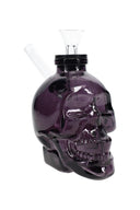 Dark purple 4-inch skull glass water pipe with black cap, clear funnel bowl, and side straw mouthpiece on white background