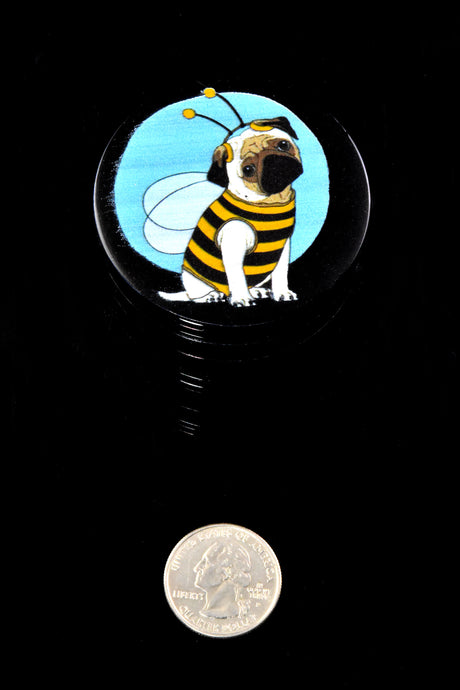 Black 56 mm four-piece aluminum herb grinder with bee-costume dog decal beside a quarter for size reference.