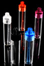 Clear snuff vials with red, blue, pink, black and clear caps and long scoop spoons, clustered on shiny black surface.