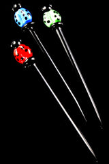 rio of 5-inch glass dab tools with black stems and red, blue, and green ladybug toppers, arranged diagonally on black background for vivid contrast.