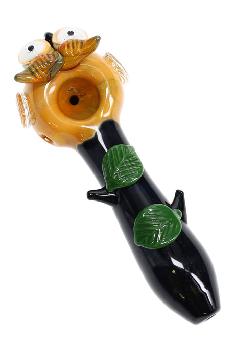 Side angle of 4½″ owl spoon pipe with amber glass bowl, black branch-style stem, and green leaf accents