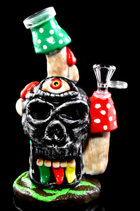 Front view of skull bong on black background highlighting the single eye, colorful tongue details, and angled mouthpiece.