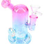 Pink and blue metallic glass mini bong, angled mouthpiece, 14 mm joint, and visible showerhead perc.