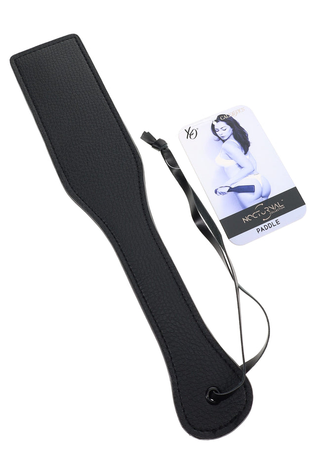 Black 12.5-inch faux leather BDSM paddle shown angled with textured surface, wrist strap and hang tag