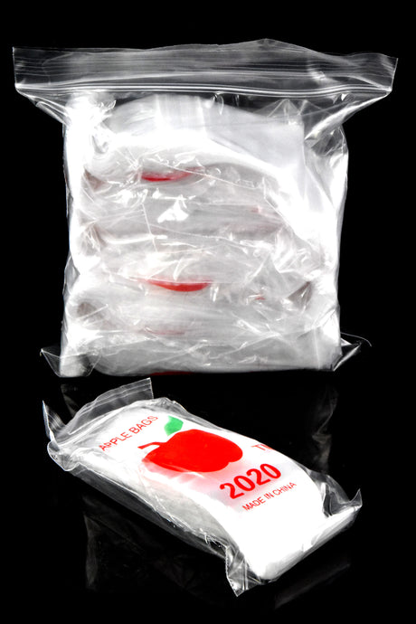 Factory-sealed bundle of Apple Bags 2-inch mini zip baggies with red apple logo resting in front of bulk pack on reflective black surface