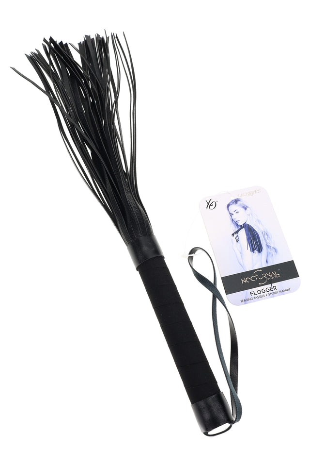Black Nocturnal flogger with multiple soft falls, textured handle, and wrist loop shown with branded hang tag; beginner-friendly impact toy.