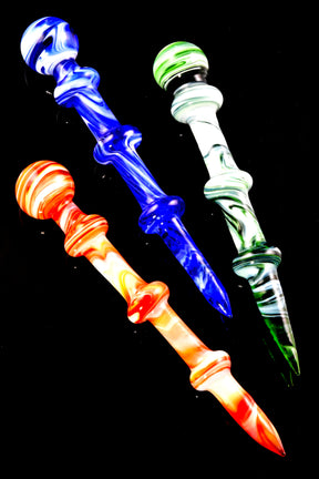 Three 6-inch marble swirl glass dab tools in blue, green, and red-orange colorways with triple-bead grips and tapered points, arranged on glossy black backdrop for vivid contrast.
