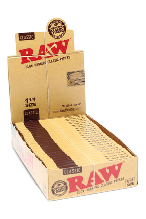 RAW Classic 1¼ rolling papers display with 24 booklets arranged in a tray, unbleached paper and vegan gum branding, slow-burning sheets.