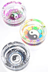 Round glass ashtray trio featuring yin-yang mandala, rainbow petal palette and black-white tribal art; clear 4-inch design with three rest notches, top view.