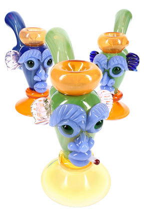 7-inch color-changing silver-fumed glass bubbler with sculpted tiki face, gold highlights, and built-in water chamber, front angled view on white background.