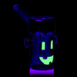 Rear UV view of MJ Arsenal Frankenbubbler glass bubbler with glowing face details and purple-lit mouthpiece