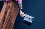 GRAV smell-proof pouch carried by wrist strap with gray fabric, black base, and compact streetwear styling