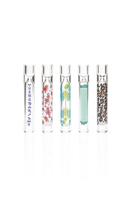 Five GRAV glass tasters with zodiac symbols, colorful starbursts, skeleton graphics, teal stripes, and leopard spots.