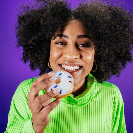 Person holding Goody Glass donut hand pipe with frosted top and sprinkle details