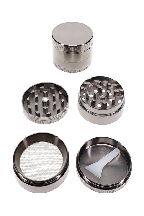 Open 4-part metal herb grinder with screen chamber, scraper, and compact 1.5 inch silver body