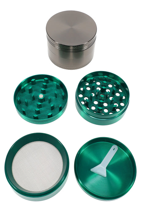 2″ 4-part metal grinder parts laid out showing teeth, screen chamber, and scraper tool, green zinc-alloy set
