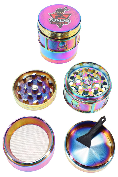Rainbow 4-part metal herb grinder by Ninja Glass, 1½″ size with mesh kief screen and scraper, components shown disassembled on white.