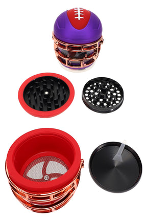 Football helmet–style 4-part metal herb grinder, 2¼″ zinc-alloy with diamond teeth, kief screen, windowed body and scraper, shown disassembled.