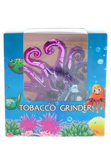 Metallic purple octopus herb grinder in sea-themed retail box with curled tentacles and raised eye details