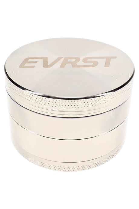Silver EVRST metal herb grinder opened to show teeth, mesh screen, collection tray, and scraper