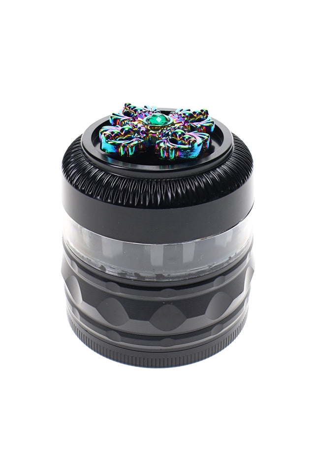 Black 4-part metal herb grinder with clear window, rainbow rhinestone spinner top, and textured grip