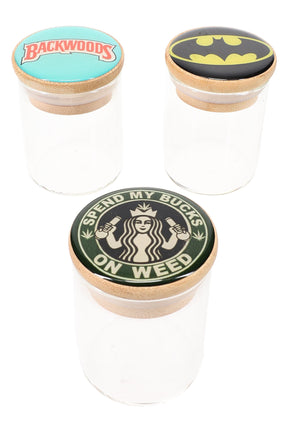 Three clear glass stash jars with bamboo lids and random decals—Backwoods logo, Batman symbol, “Spend My Bucks on Weed”—displayed on white background