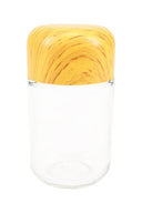 Tall clear glass storage jar featuring square-shouldered yellow wood-grain tamper cap, shown upright on white backdrop for size comparison