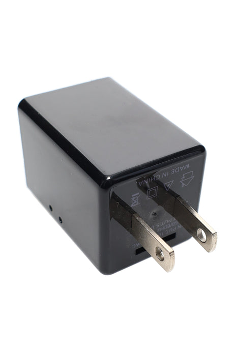 Rear view of covert USB charger camera showing U.S. AC prongs and subtle ventilation holes, positioned on white backdrop
