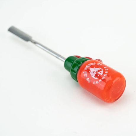 Reverse angled image of Sriracha dabber showcasing flat bottle bottom, glossy glass surface, and full length of stainless scoop on white background.