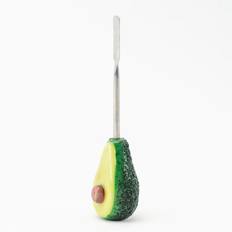 Side profile of avocado dab tool showing speckled peel texture, creamy interior, and full metal scoop against white studio background.