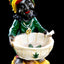 Standing Rasta figurine resin ashtray holding cream bowl with leaf decor, vibrant green shirt and woven cap, black backdrop.
