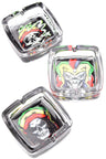Square glass ashtray trio with reggae skull and jester designs in vivid Rasta colors, glossy white backdrop.