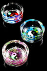 Three yin-yang themed 3.25-inch tempered glass ashtrays in bright mandala and cosmic hues, top-down view.