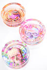 Large round glass ashtrays displaying cupcake sugar skull, hypnotic swirl skull and gingham floral skull artwork; thick crystal build shown in bright flat-lay.