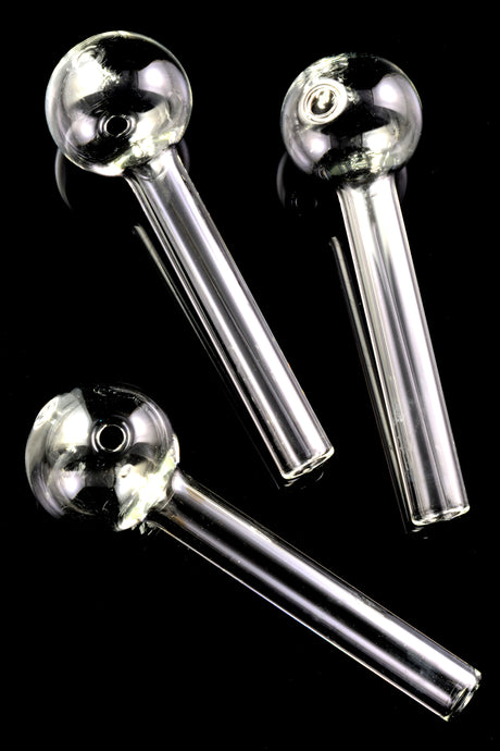Cluster of three 4-inch clear thick-walled glass oil burner pipes on glossy black surface, showcasing round bowl ends