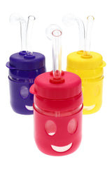 US-made smiley face oil burner rig with colorful protective sleeve, clear bubble burner, and angled glass mouthpiece; assorted colors.
