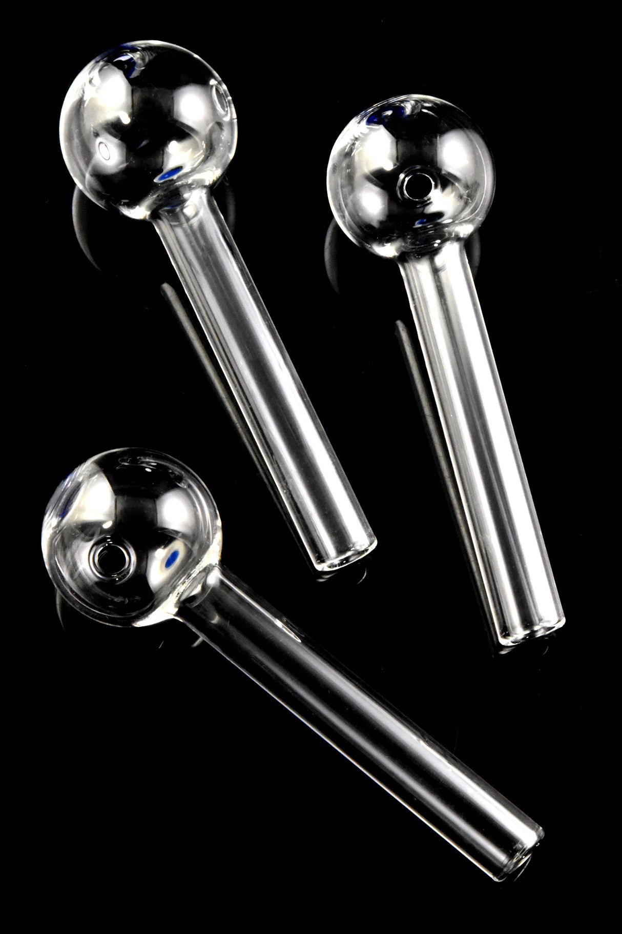 Three thick glass oil burner pipes with blue dot accents, diagonally arranged on glossy black background for full-stem view.