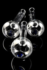 Close-up of three thick glass oil burner pipe bowls with blue dot accents, viewed from above on glossy black background.