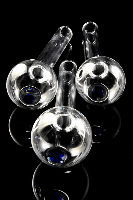 Close-up of three thick glass oil burner pipe bowls with blue dot accents, viewed from above on glossy black background.