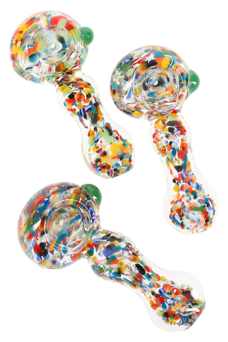 Clear 3.5-inch borosilicate spoon pipe filled with vibrant multicolor confetti frit, deep bowl and side carb visible on white backdrop.