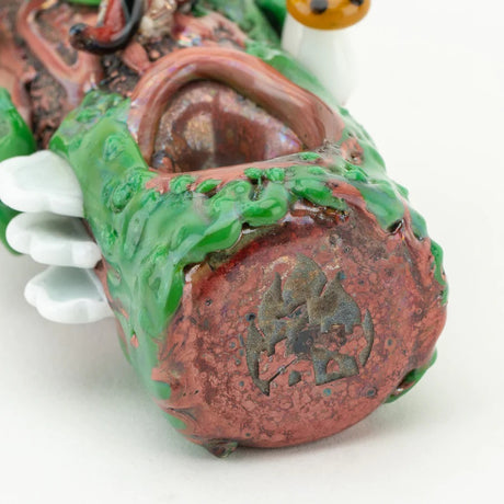 Close-up of glass hand pipe mushrooms and moss texture on a brown log-style dry herb pipe