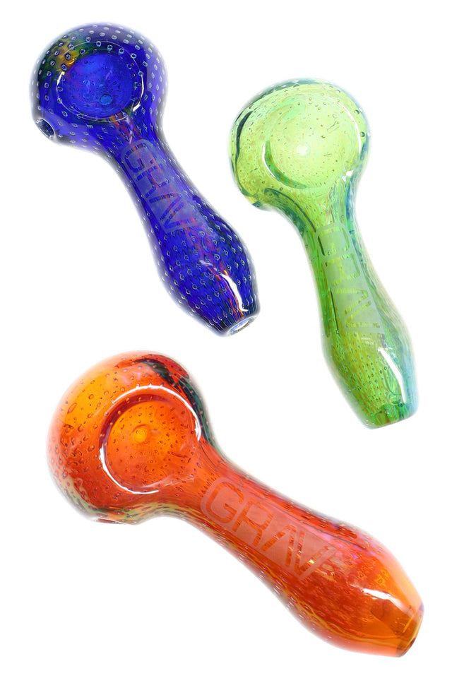 Trio of GRAV 4″ bubble trap glass spoon pipes in blue, green, and amber with textured, sparkling finish on white background.
