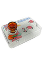 Transparent black arcade controller glass hand pipe with amber joystick bowl and pink-red buttons resting on a white studio background.