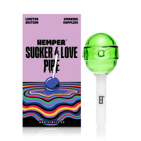 Green lollipop hand pipe standing beside Hemper retail box, showing round candy head and clean stick mouthpiece