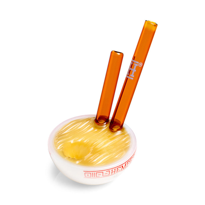 Top angle ramen bowl glass hand pipe highlighting textured noodle surface and twin amber chopstick details, fun display