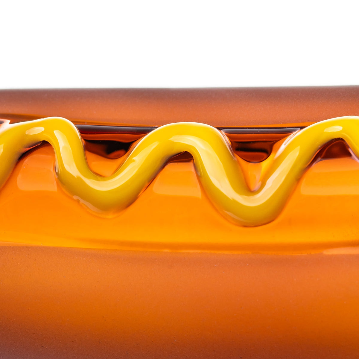 Close-up of BigFun! Glizzy hot dog hand pipe showing the glossy raised yellow mustard swirl over amber glass