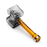 Hemper glass hand pipe lying diagonally with sculpted smoky warhammer head and translucent amber handle
