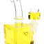 Yellow fluid-filled cube bong close-up with square chamber, curved neck, and glass bowl attachment.