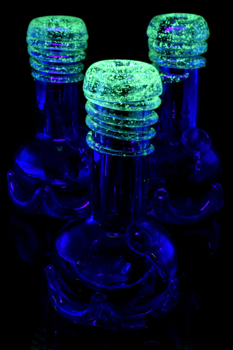 Three 7-inch rainbow metallic beaker bongs with thick bases and iridescent glass finish arranged on white background, front view.